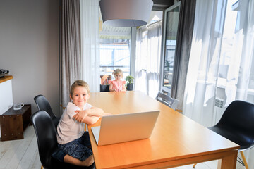 A person sitting at a table with a laptop and smiling at the camera.