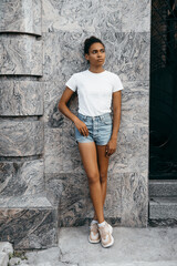 portrait of attractive afro american woman on shorts and t-shorts at gray background 