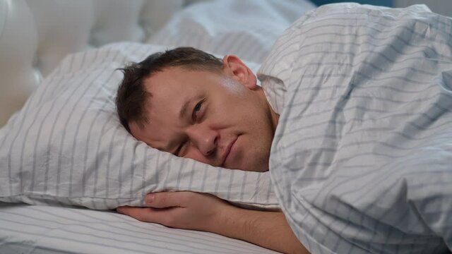 A man lies on the bed, tossing and turning, cannot sleep, gets up