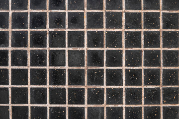 wall with gray stains of dirt, black square ceramic tiles with light cement. rough surface texture