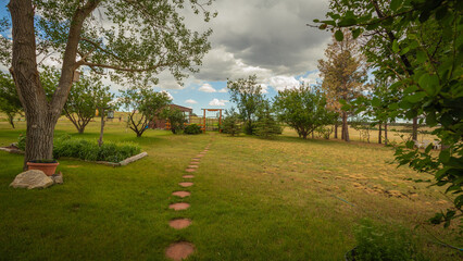 Back yard landscape on the Colorado prairie near Denver with garden path, trees, and log gate in the distance