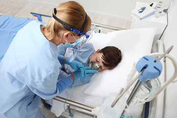 nurse takes care of the patient child in hospital bed playing with teddy bear, wearing protective masks, corona virus covid 19 protection concept,