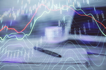 Double exposure of financial graph drawings and desk with open notebook background. Concept of forex market