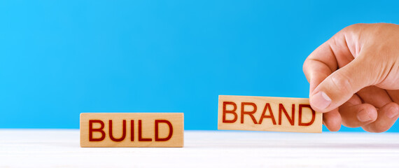 build your brand concept. a man puts wooden blocks in the inscription build brand