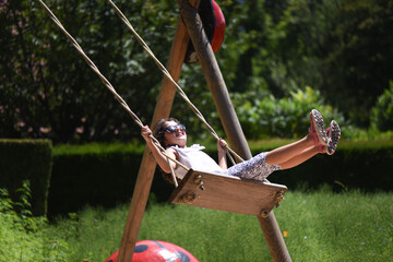 Girl on a swing. Girl with long hair. In the summer park for children.