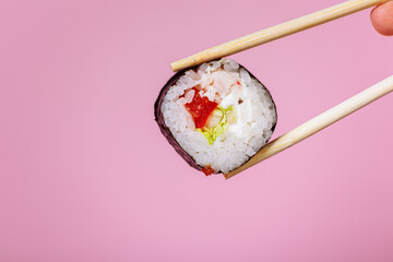 Tasty sushi roll maki with wooden chopsticks on pink background close up. Place for caption and text