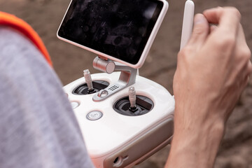 Man holding an white controller and operating a drone  with black screen view