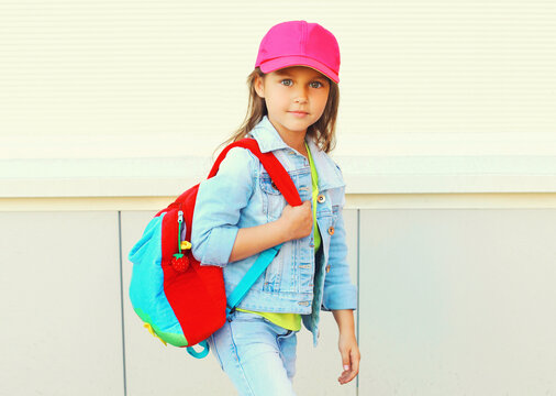 Portrait Of Little Girl Child Wearing A Baseball Cap With Backpack On Background