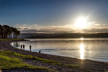 Family and dog by a loch at sunset