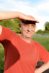 Obraz premium Old man wearing elegant red shirt very happy and smiling looking far away with hand over head. High quality photo