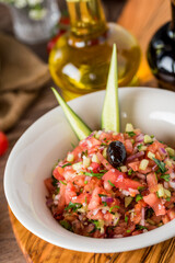 Healthy mixed salad in white bowl on wooden table.