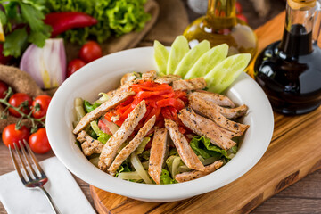 Healthy mixed salad in white bowl on wooden table.