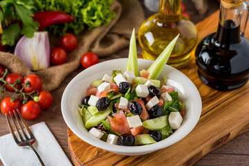 Healthy mixed salad in white bowl on wooden table.