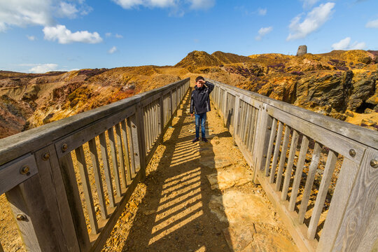 Small boy in bright sunshine on footbridge on stony mountain, Parys Mountain.