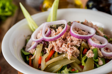 Healthy mixed salad in white bowl on wooden table.