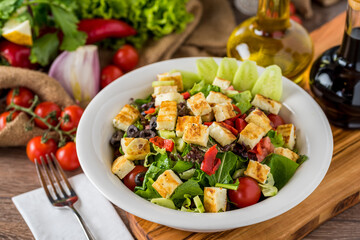Healthy mixed salad in white bowl on wooden table.