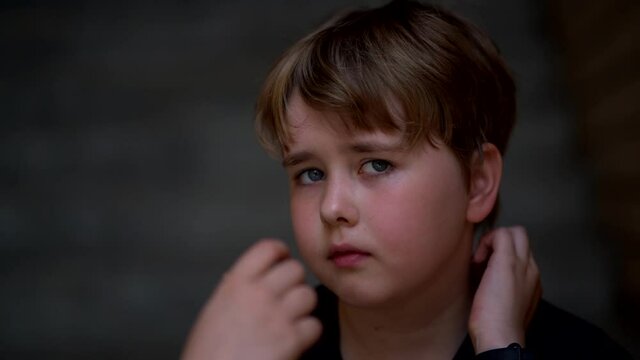 Close-up portrait of a young girl with short hair and plump cheeks. She looks up and blinks. Slow motion.