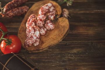 Slices of salami with tomatoes on a cutting board on a wooden table. Selective focus..