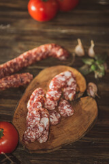 Slices of salami with tomatoes on a cutting board on a wooden table. Selective focus..