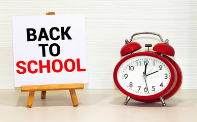 Alarm clock and school supplies on blue background. Back to school concept. Education concept