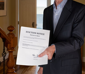 Open front door with man in suit handing an eviction notice to a defaulting renter in modern home...