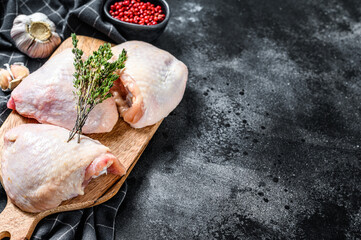 Fresh chicken thigh with skin on cutting board, organic meat. Black background. Top view. Copy space