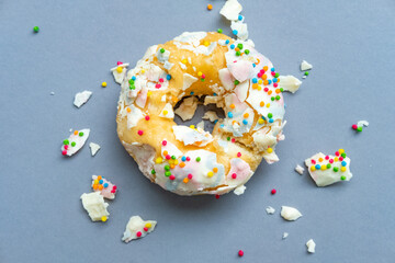 The destroyed doughnut lies on a uniform background. Donut, Slice of Food, Healthy Eating, Chart, Dieting. An overhead view of a doughnut with colored sprinkles. Unhealthy eating