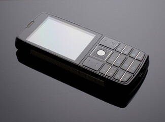 old push-button cell phone on a dark background. white background.