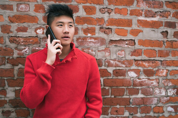 Asian man talking on the phone outdoors.