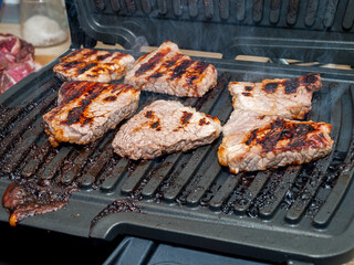 pieces of meat fried on an electric grill, steaks from meat, proper roasting of the grill