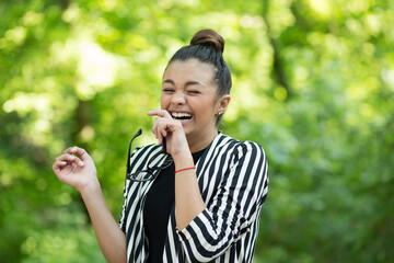 Fototapeta premium woman holding eyeglasses laughing happily outside
