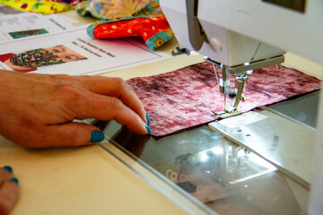 Close-up of a hand moving fabric for a mask on a sewing machine