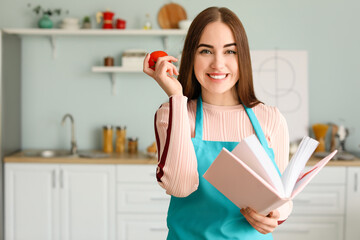 Young woman with recipe book in kitchen