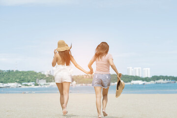 two women touching hands on the beach, vacation, summer time
