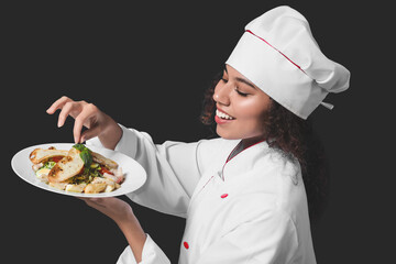 Female African-American chef with tasty dish on dark background