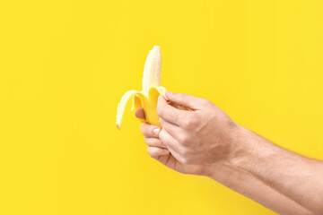 Fototapeta na wymiar Man peeling banana on color background