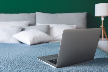 Modern laptop on bed in room
