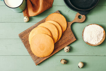 Board with tasty pancakes on table