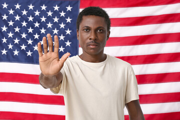Sad African-American man showing stop gesture near national flag of USA. Stop racism