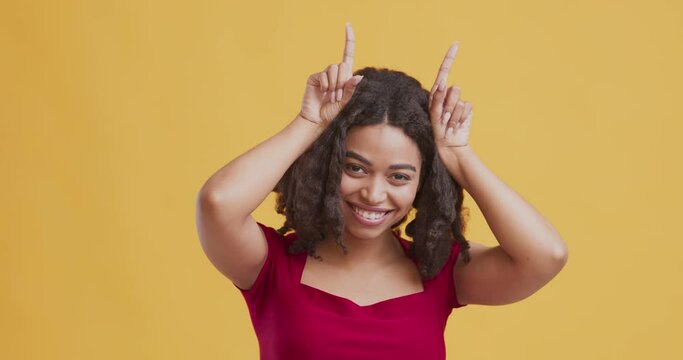 Playful young black woman standing with bull horn gesture