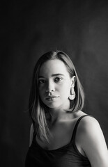 black white portrait of a beautiful girl with big lips and a large earring. Girl in black mask on gray background