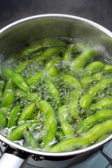 The edamame is being cooked in a pot.