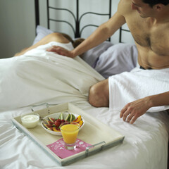 Obraz na płótnie Canvas Man serving a tray of breakfast for is sleeping wife