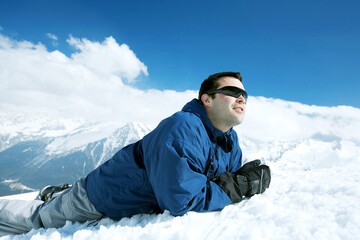 Fototapeta na wymiar Man in warm clothing lying forward on snowy mountain