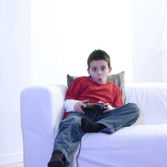 Boy sitting on the couch playing with video game console
