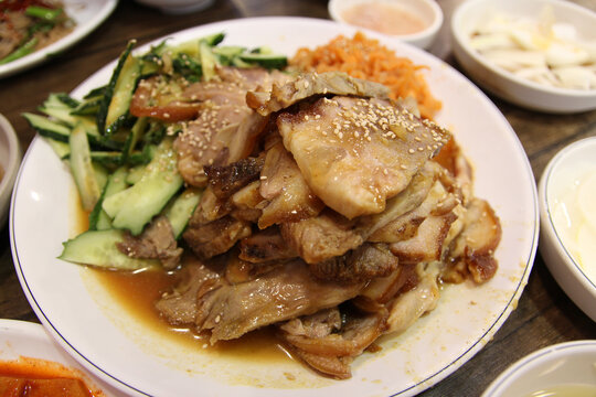 Korean style braised pork belly with the side dishes cucumber and edible jellyfish at Korean restaurant, South Korea