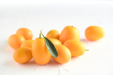 Kumquats, small exotic citrus fruits, on a white textured background