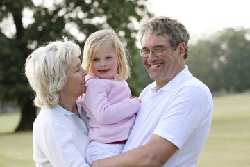Fototapeta premium Senior man and woman with cute girl in the park