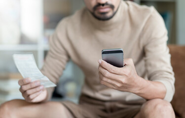 Young man using mobile phone pay bill with application  payment during stay at home