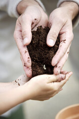 Man passing a handful of soil to girl